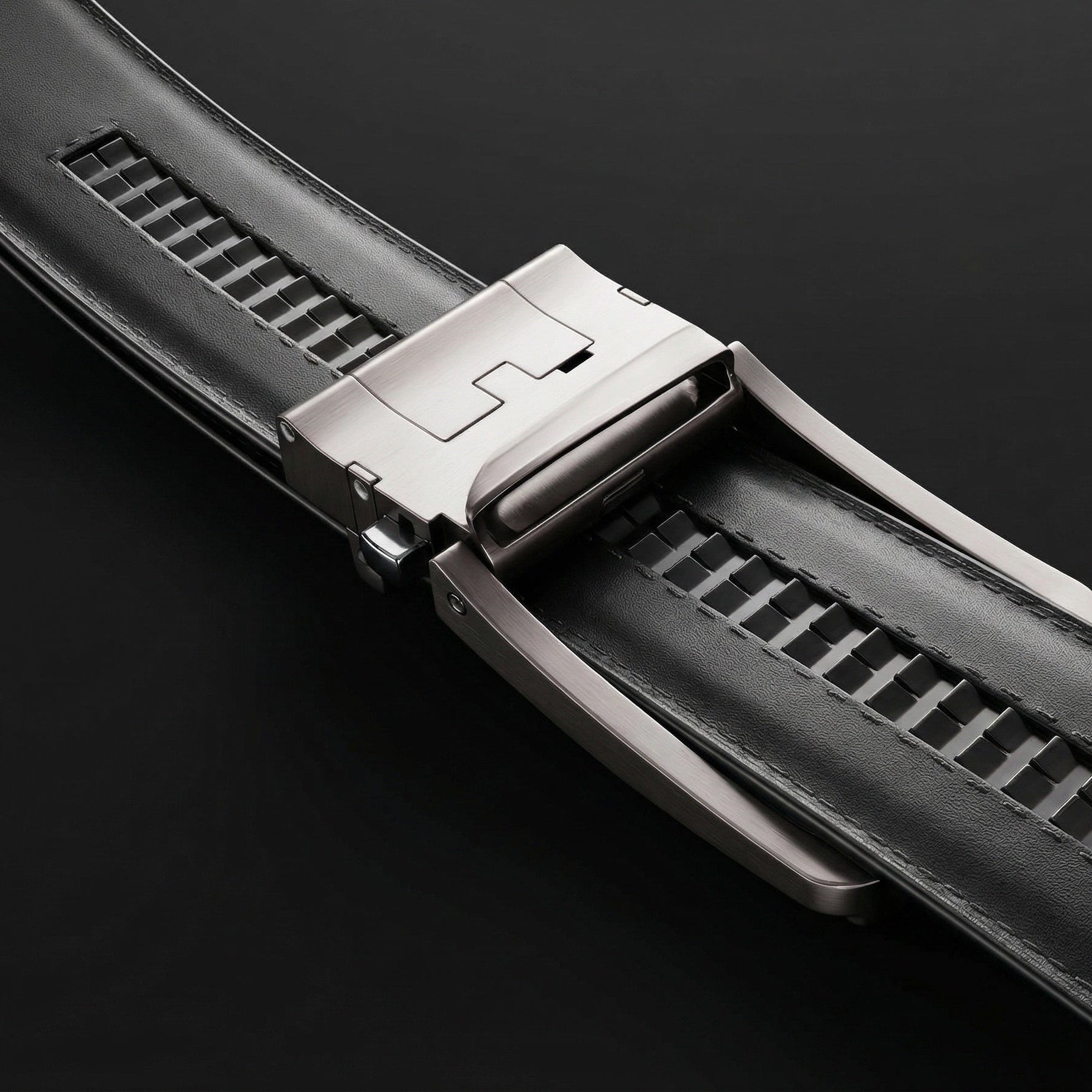 Close-up of a black watch strap with a metallic clasp on a dark background