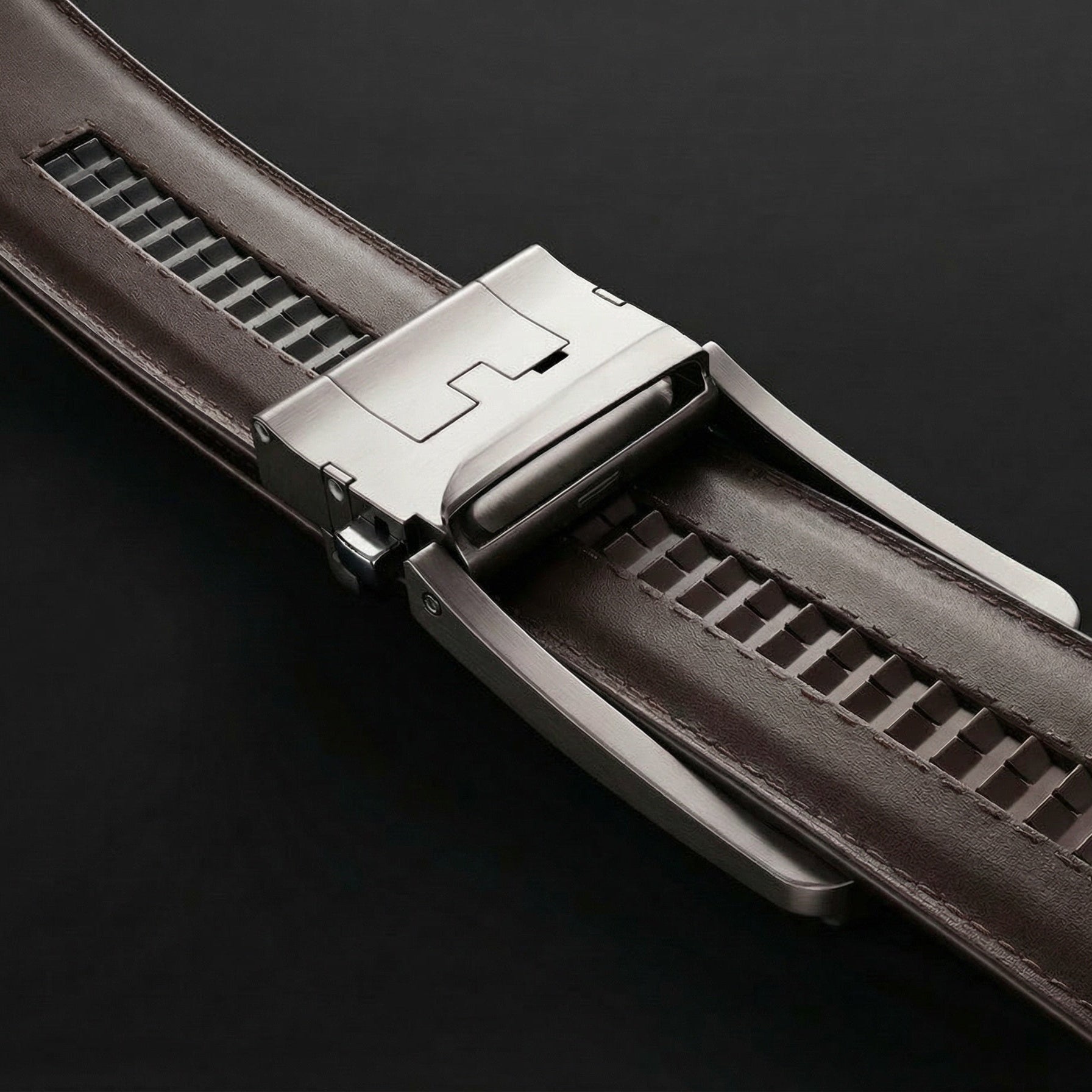 Close-up of a brown leather watch strap with a silver clasp on a black background